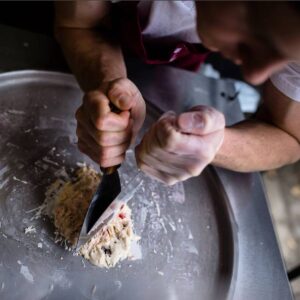 Person rolling ice cream on platter with tools